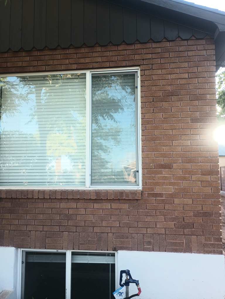 Large sliding window with fresh screen installed on a brick home in St. George